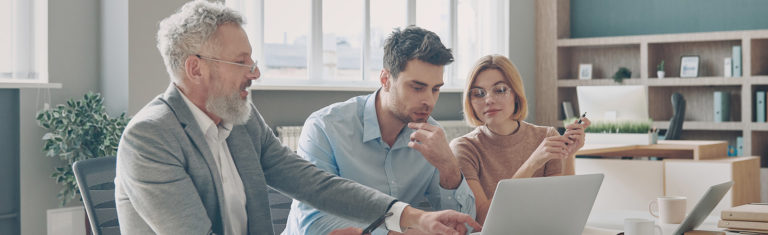 Three confident business people having discussion while working in the office together